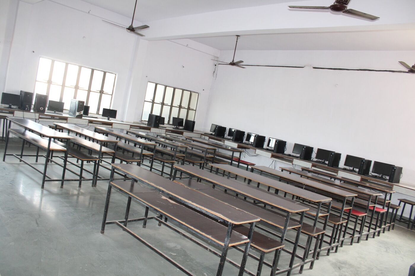Spacious classroom with bench rows, ceiling fans and large windows