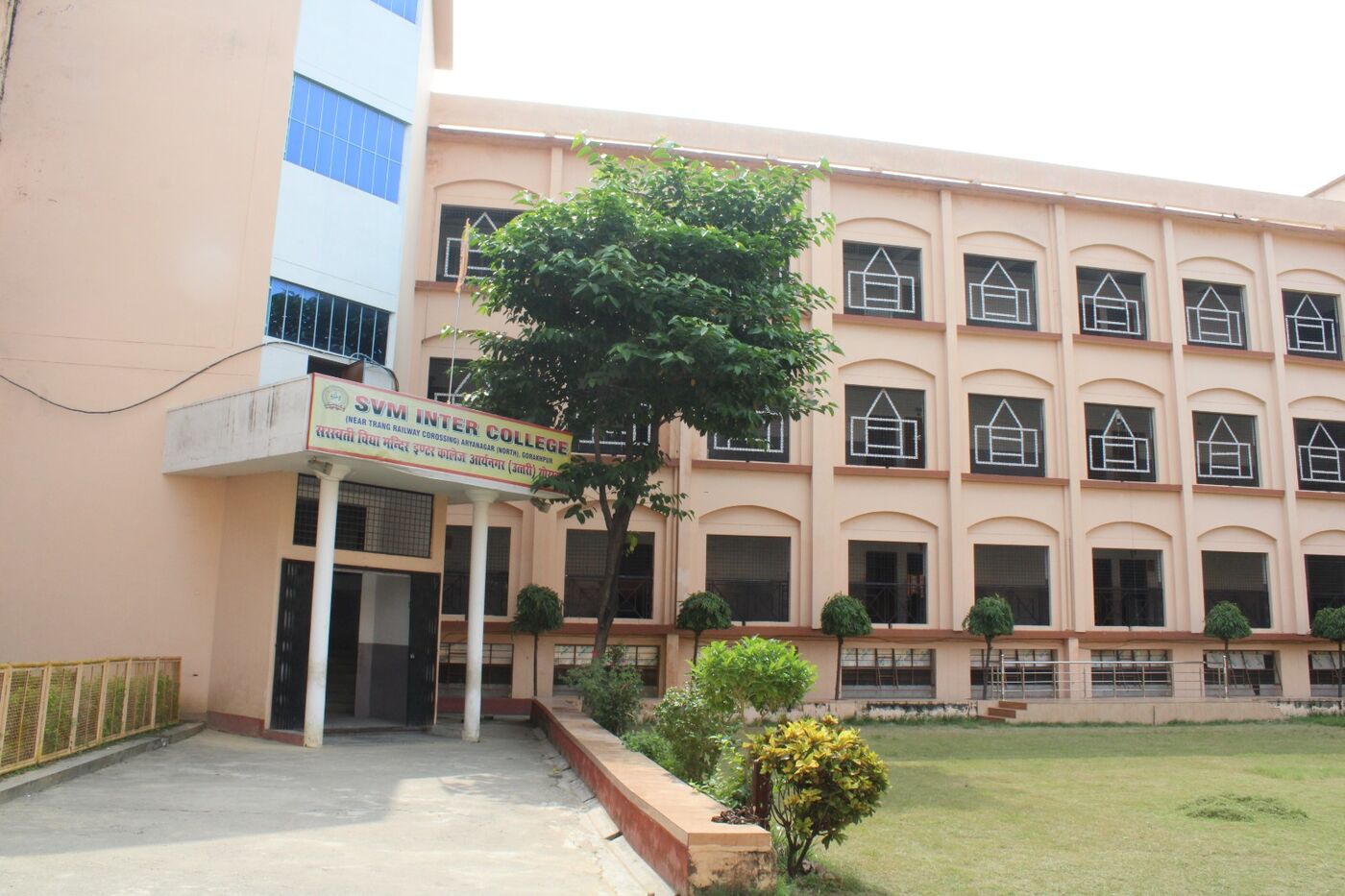 Front entrance block of SVM Inter College with the name board and a shade tree