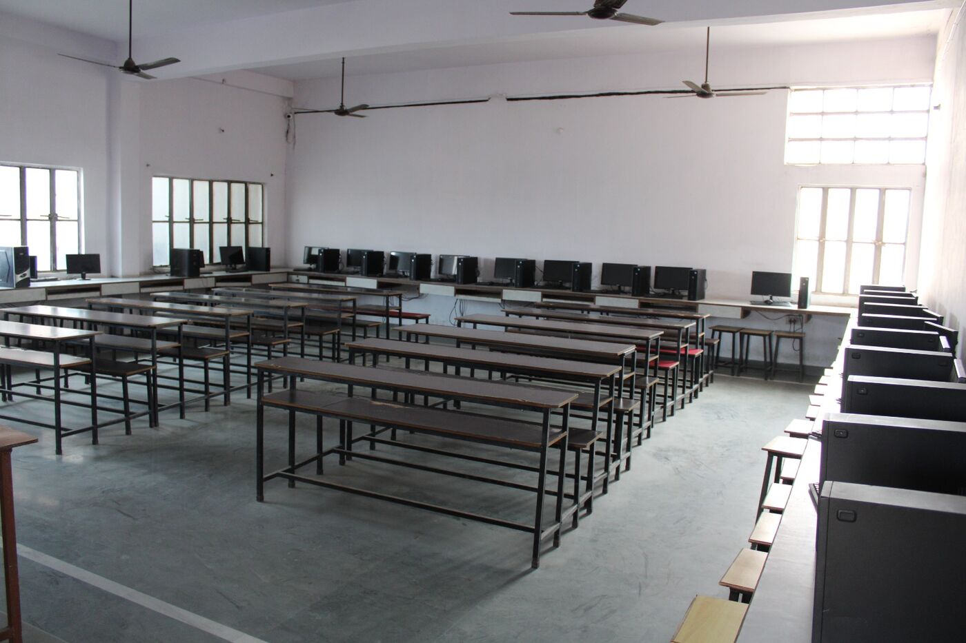 Empty classroom with rows of wooden benches and desks